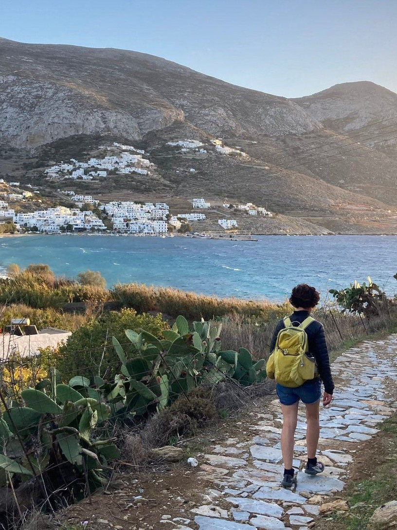 A hiker on a paved path above the bay of Amorgos in the Cyclades
